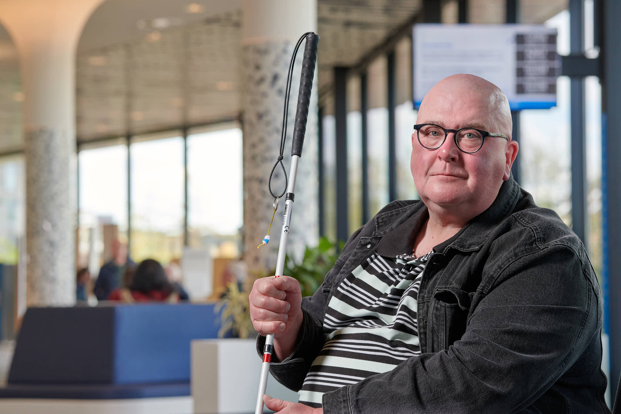 Man met bril en blindegeleidestok.