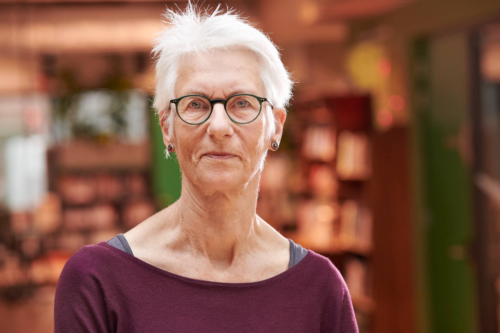 Mevrouw met bril en bruine trui.