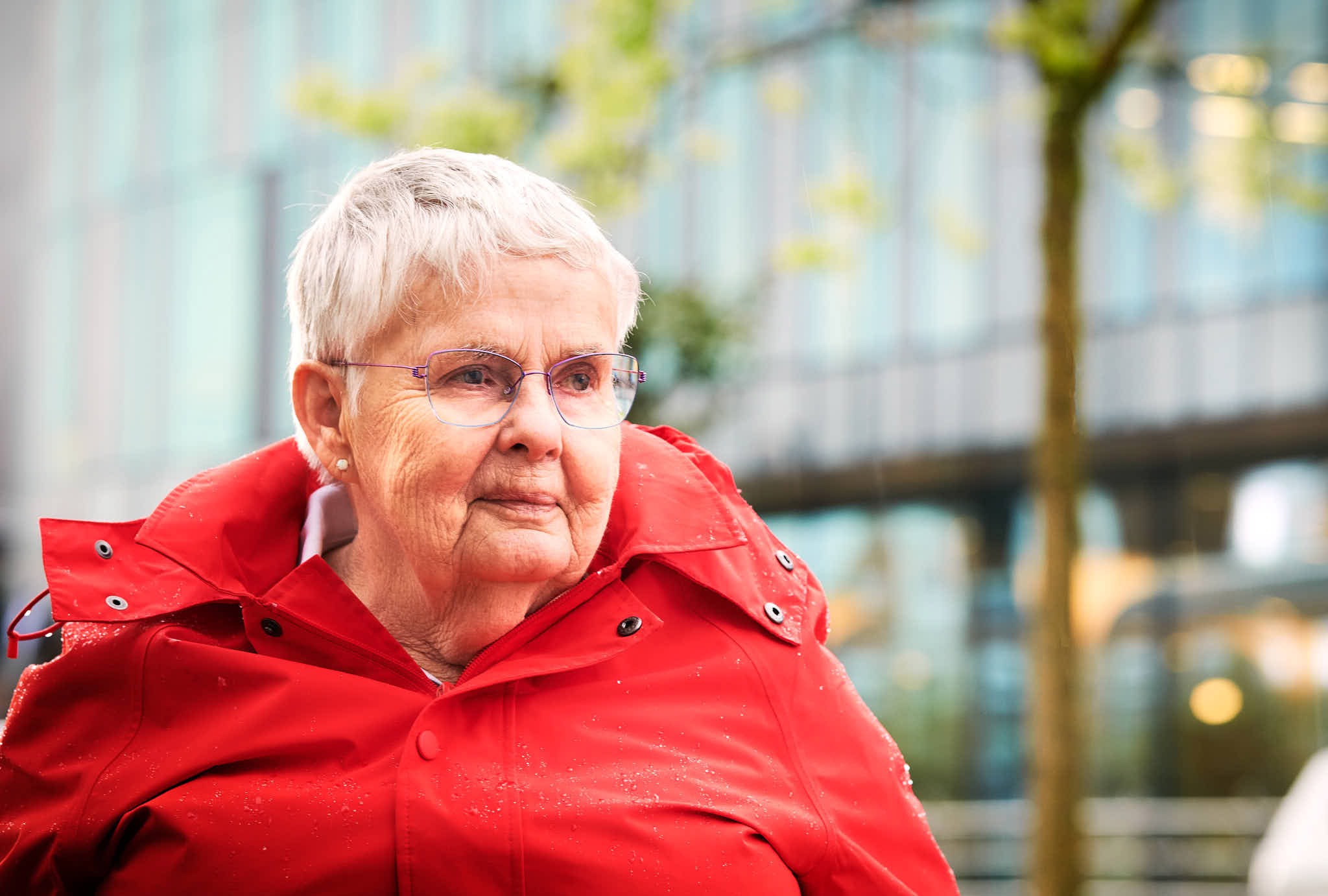 Mevrouw met bril en rode jas.