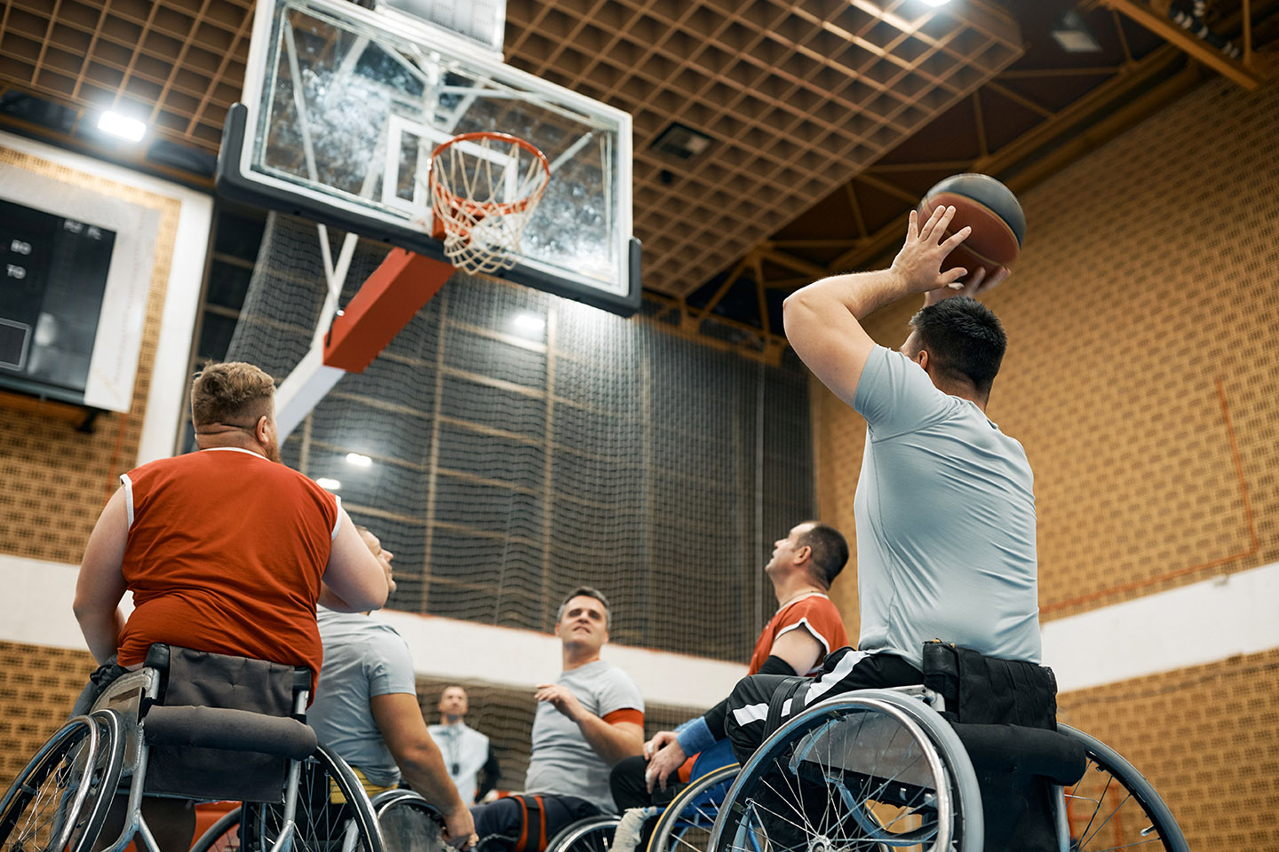 Personen in een rolstoel die basketbal spelen.