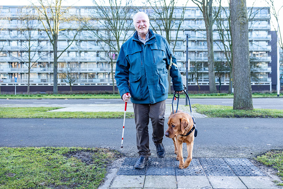 Man met hond en blindegeleidestok.